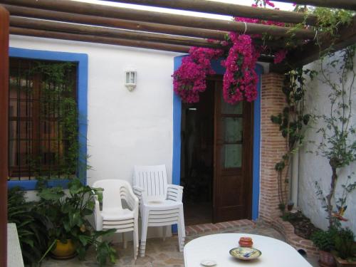 a patio with two chairs and a table and flowers at Casablanca in Yunquera