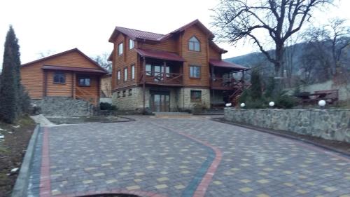 a large wooden house with a stone driveway at Karpatska Mria in Yaremche