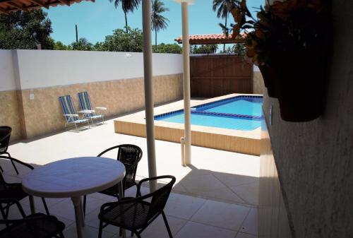 a patio with a table and chairs and a swimming pool at Pousada Espaço Litoral in Baixio