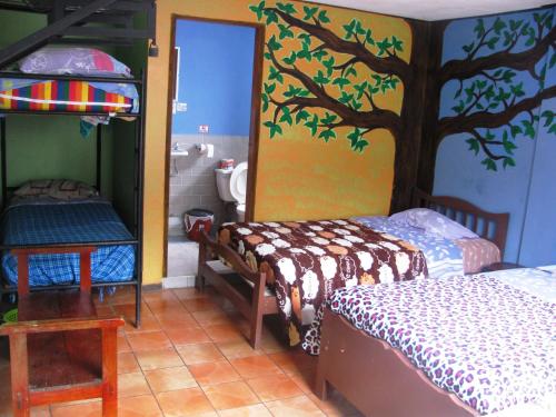 a bedroom with two beds and a tree painted on the wall at Transilvania in Baños