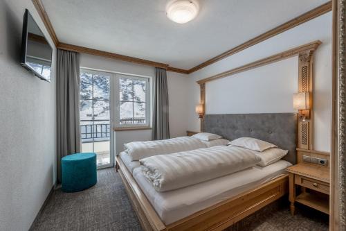 a bedroom with a bed and a large window at Landhaus Jenewein in Obergurgl