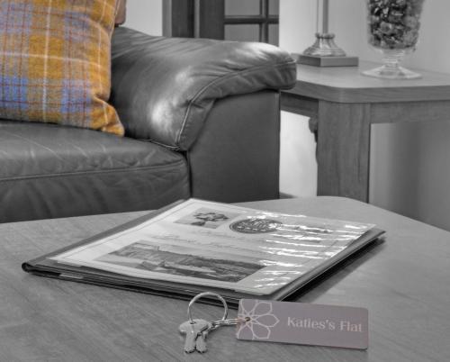 a book on a table with a pair of keys at Katie's Flat in Oban