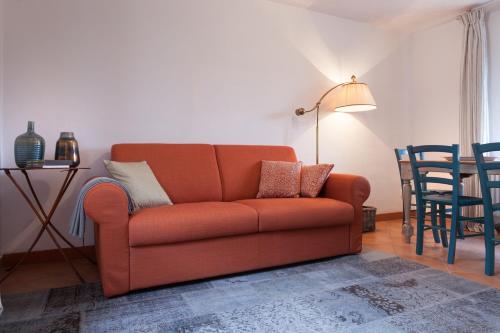 a living room with an orange couch and a table at COLVAGO CIMA DODICI – DOLOMITES NATIONAL PARK in Santa Giustina