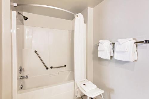 a white bathroom with a shower and white towels at Sage Inn Merritt BC in Merritt