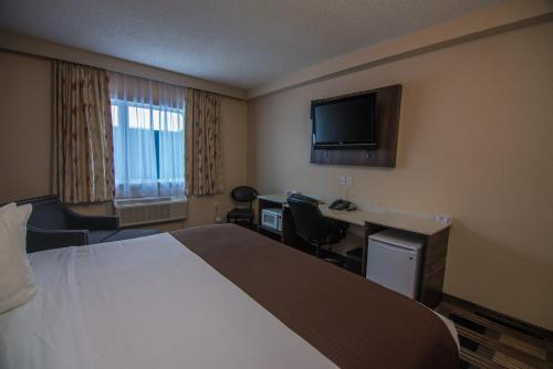 a hotel room with a bed and a desk and a television at Baymont by Wyndham Medicine Hat in Medicine Hat