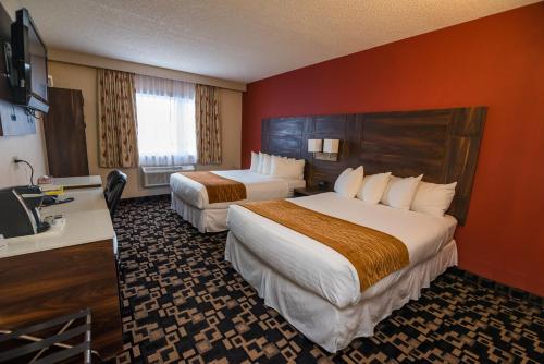 a hotel room with two beds and a desk at Baymont by Wyndham Medicine Hat in Medicine Hat
