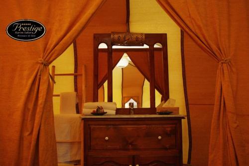 a bathroom with a mirror and a dresser with a sink at Karim Sahara Prestige in Zagora