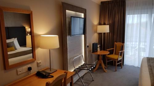 a hotel room with a bed and a desk and a mirror at Heywood Spa Hotel in Tenby
