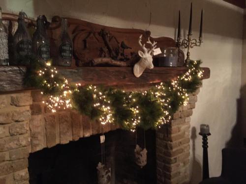 a fireplace with a christmas wreath and lights at Hotel Ten Lande in Beernem
