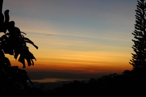 a sunset in the sky with trees in the foreground at Hotel Flor de Bromelia in Monteverde Costa Rica