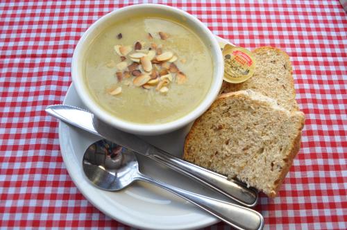 a bowl of soup on a plate with a sandwich at The Sleeping Moose Cottage in Birch Plain