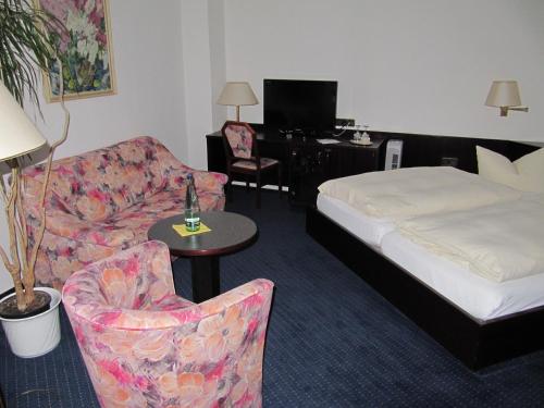a hotel room with a bed and a couch and chair at Hotel Wettin in Treuen