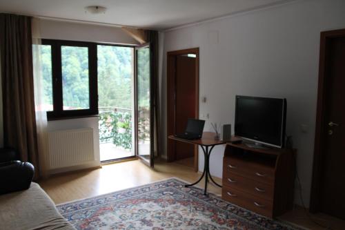 a living room with a television on a dresser with a table at Studio Lalelelor in Sinaia