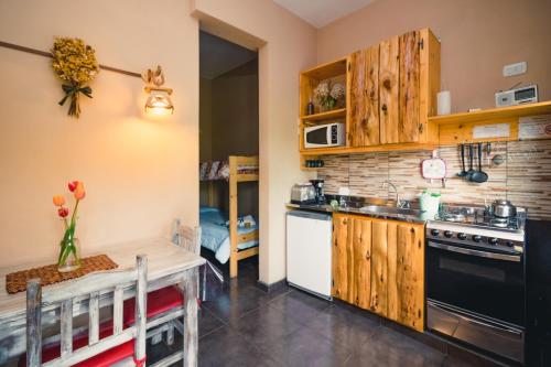 a kitchen with wooden cabinets and a sink and a stove at Cabañas Niuke & Apart Fraschetti in El Bolsón