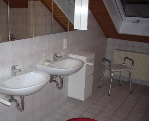 łazienka z 2 umywalkami i krzesłem w obiekcie Ferienwohnung Lahntal/Taunus w mieście Hochelheim