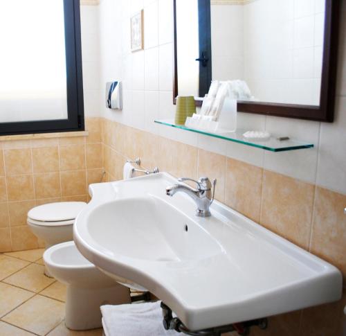 a white toilet sitting next to a sink in a bathroom at Greta Rooms Hotel in Mazara del Vallo