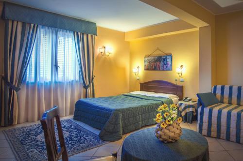 マツァーラ・デル・ヴァッロにあるGreta Rooms Hotelのベッド2台、ソファ、テーブルが備わるホテルルームです。