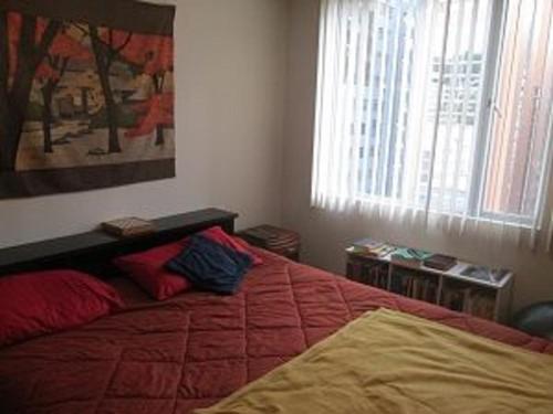 Un dormitorio con una cama con sábanas rojas y una ventana en Carolina Family Suite, en Quito