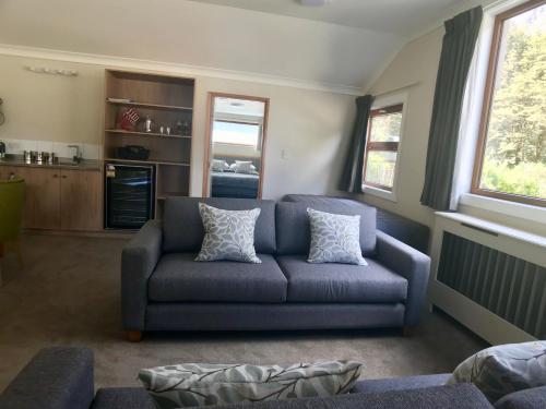 a living room with a blue couch and two pillows at Arthur's Pass Motel & Lodge in Arthur's Pass