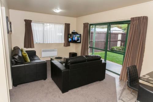 a living room with two leather couches and a tv at Oamaru TOP 10 Holiday Park in Oamaru