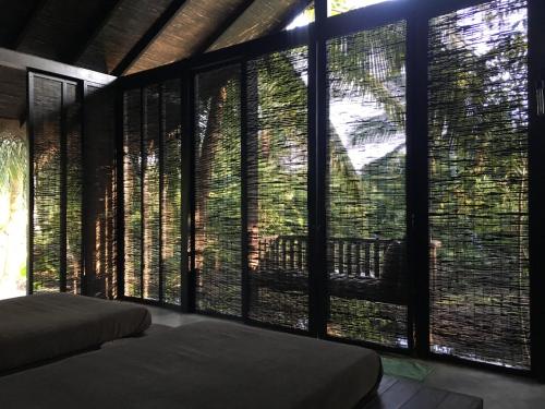 a bedroom with a large window with blinds on it at KAJU GREEN eco lodges in Unawatuna