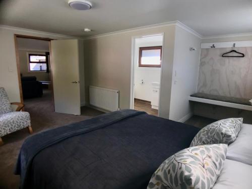 a bedroom with a bed and a chair and two windows at Arthur's Pass Motel & Lodge in Arthur's Pass