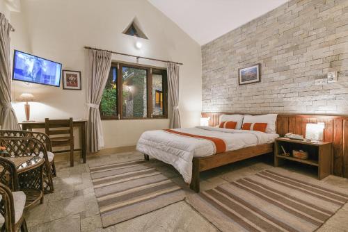 a bedroom with a bed and a brick wall at Mum's Garden Resort in Pokhara