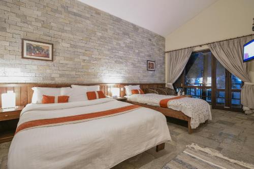 a bedroom with two beds and a brick wall at Mum's Garden Resort in Pokhara