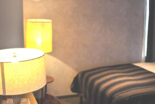 a room with a bed and a lamp and a stool at Hotel The Knot Yokohama in Yokohama