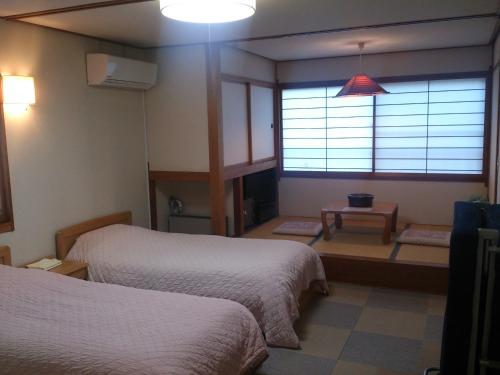 野沢温泉村にあるヴィラ・クボタのベッド2台と窓が備わるホテルルームです。
