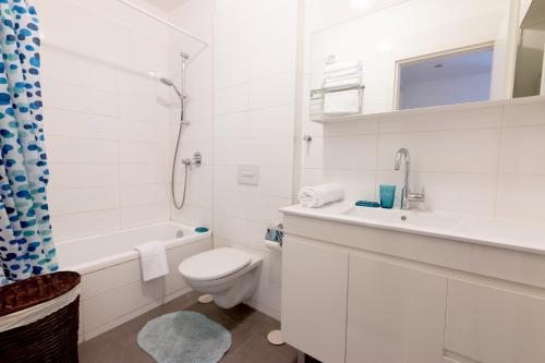 a white bathroom with a toilet and a sink at Bright 2 BR in Hype Neighborhood by FeelHome in Tel Aviv
