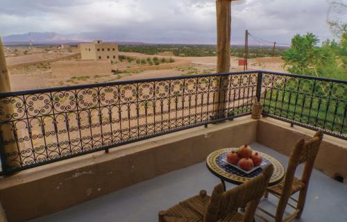 a balcony with two chairs and a table with fruit on it at Taloute Ecolodge in Skoura