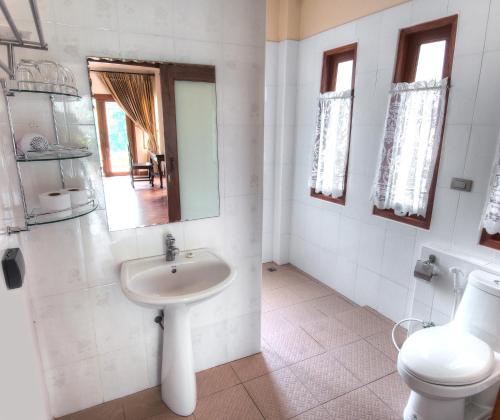 a bathroom with a sink and a toilet and a mirror at Khanom Hill Resort in Khanom