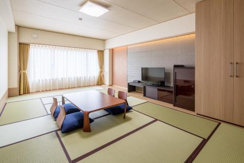a living room with a table and a tv at Hakone Kogen Hotel in Hakone