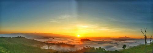 a misty sunrise in the mountains with the sun setting at Cave Lodge in Pang Mapha