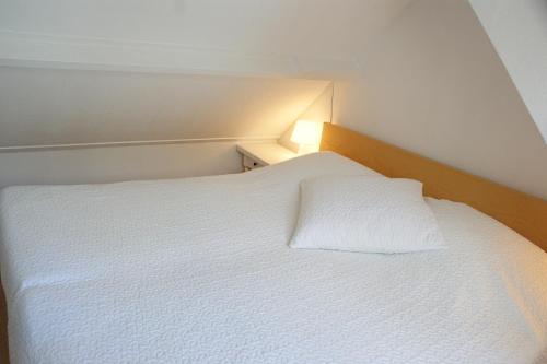 エグモント・アーン・ゼーにあるEgmondaanzeevakantiehuisjeのベッドルーム(白いベッド、白い枕付)