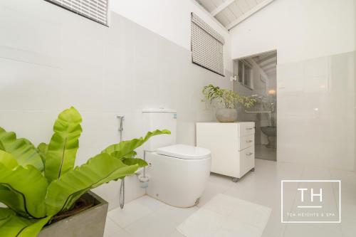 a white bathroom with a toilet and a plant at Tea Heights in Kandy