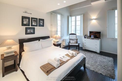 una camera con un grande letto bianco e una sedia di Horti Della Fasanara a Ferrara