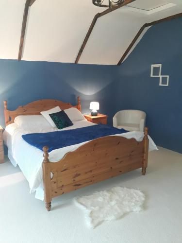 a bedroom with a wooden bed with a blue wall at Sams cottage in Corderry