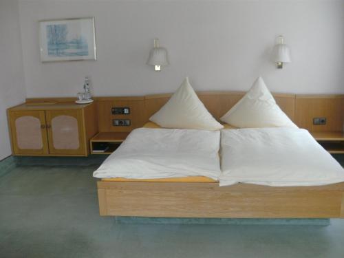 a bed with white sheets and pillows in a room at Waldhotel Tropfsteinhöhle in Wiehl