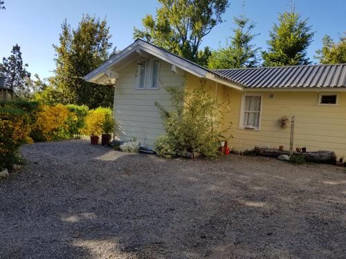 una casa amarilla con una entrada de grava delante de ella en Magda, en Villa La Angostura