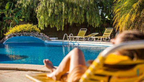 a woman laying on a lounge chair next to a swimming pool at Hotel Palmar in Colón