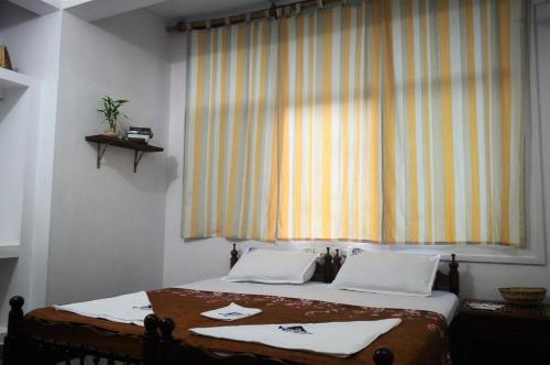 a bedroom with a bed with two pillows and a window at Panchavadi Ayurvedic Beach Resort in Varkala