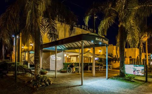 a bus stop in front of a building with palm trees at Hotel Palmar in Colón
