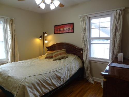a bedroom with a bed and two windows at Covered By Faith Rentals -Storybook Home in Rochester