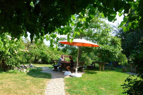 a man and woman sitting on a bench under an umbrella at Altes Gehöft am Lormanberg in Kirchberg an der Raab