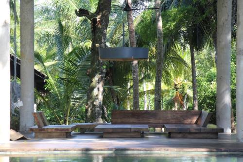 a swimming pool with two benches and a bucket at KAJU GREEN eco lodges in Unawatuna