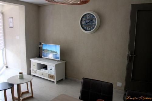 a living room with a tv and a clock on the wall at Le flamant - Appartement P2 de 40m2 grande terrasse-parking-wifi in La Grande-Motte