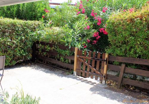 a wooden fence with pink flowers and bushes at Le flamant - Appartement P2 de 40m2 grande terrasse-parking-wifi in La Grande-Motte