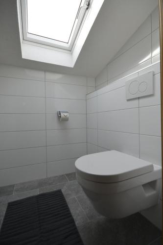 une salle de bains blanche avec des toilettes et une lucarne. dans l'établissement Haus Triumph, à Pettneu am Arlberg